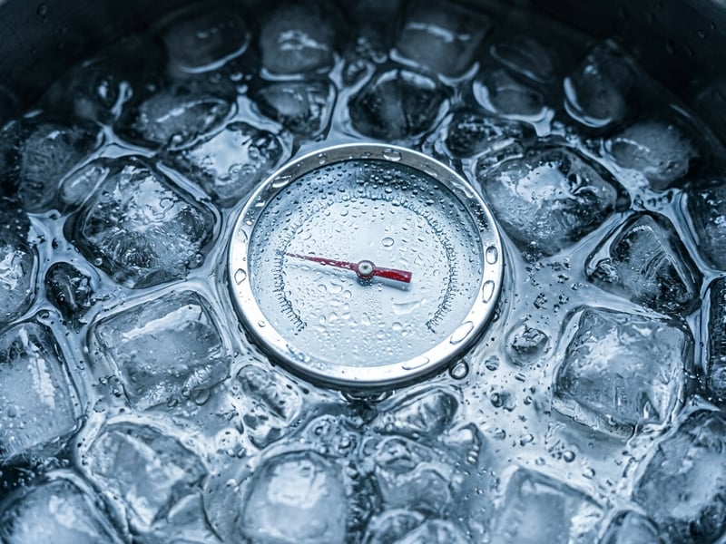 A floating thermometer among ice cubes in cold water