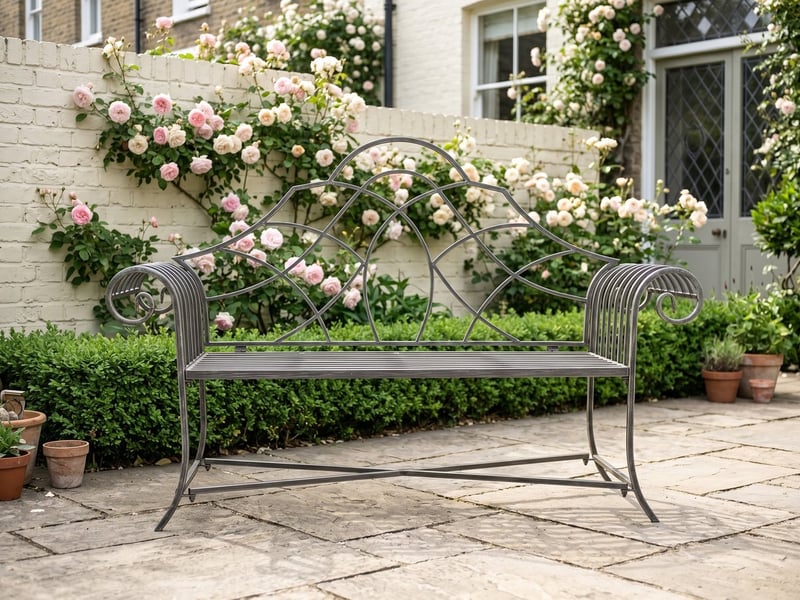 Mayfair grey Lutyens-style metal garden bench on a York stone patio with climbing roses behind