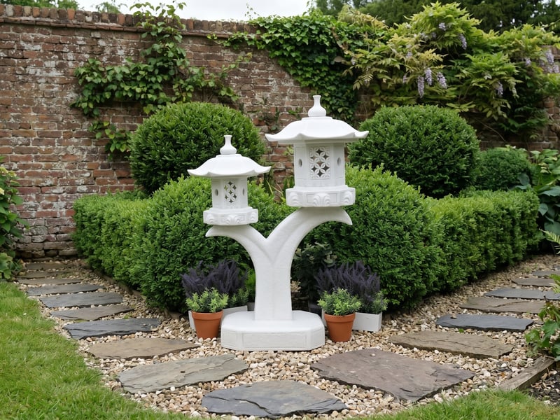 White double cantilever pagoda ornament at the turn of a stepping-stone path in a brick-walled UK garden with clipped evergreens
