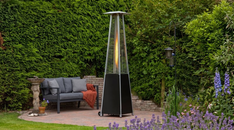 Lifestyle Tahiti II black pyramid flame heater beside a garden bench on an evening patio