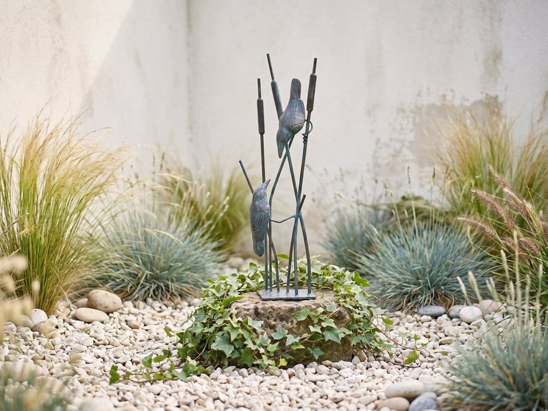 Bronzed songbirds on reeds garden ornament among lavender and roses in a coastal garden border