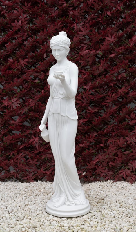Hebe mythological garden statue UK in white finish holding a goblet of nectar in a cottage garden