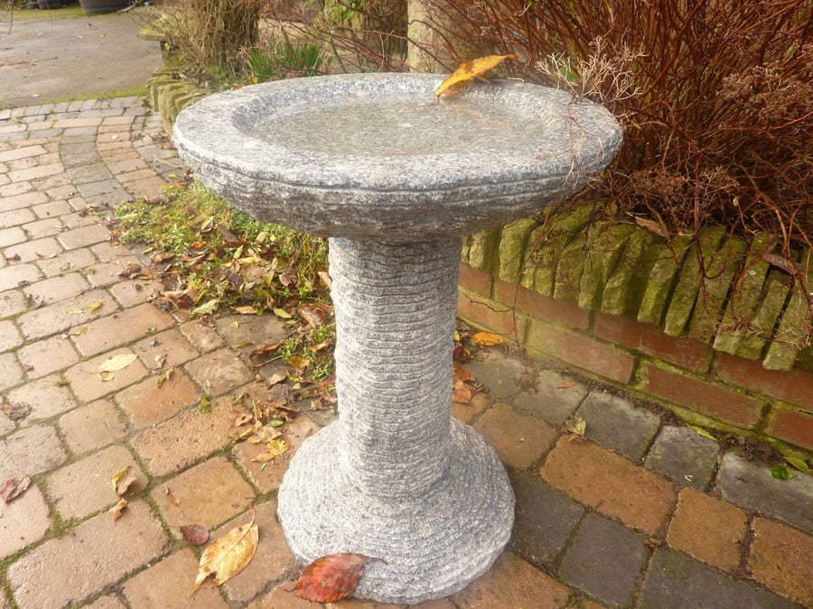 Cascade grey granite bird bath with naturally textured rim and shallow basin in a UK wildlife garden border