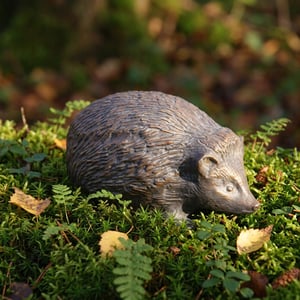 Metal hedgehog garden ornament with bronzed patina in a UK garden border