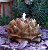 Artichoke stone fountain with cascading water in a slate reservoir bed