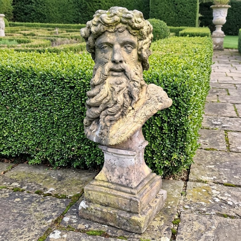 Hercules bust on a stone pedestal in a formal Georgian garden
