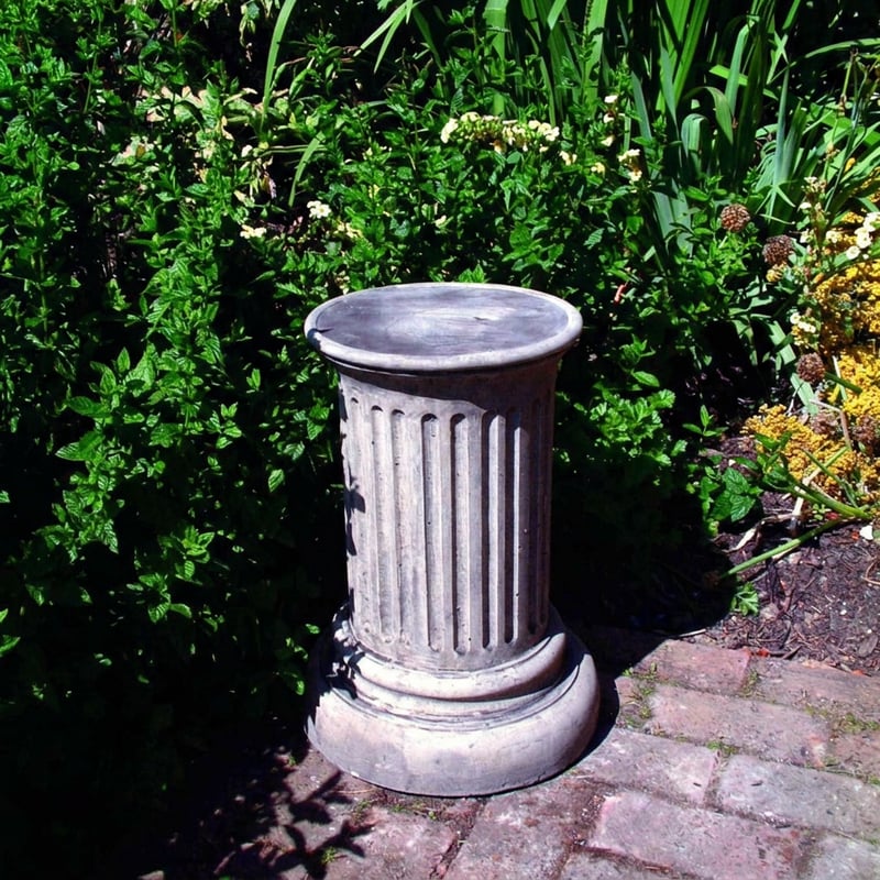 Doric column stone garden pedestal in Cotswold stone finish in a traditional English garden
