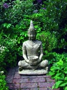 Serene Buddha stone fountain in stone finish sat on a brick garden path