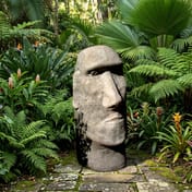 Stone Moai Head Statue in a tropical garden setting with ferns and exotic plants