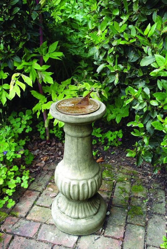 Aged brass sundial mounted on a Victorian stone garden pedestal