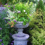 Flemish Stone Garden Vase planted with flowers in a garden setting