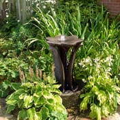 Flower Stone Fountain in garden border with lush green plants