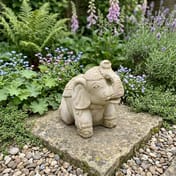 Indian Elephant Stone Garden Ornament in a garden setting with flowers and plants