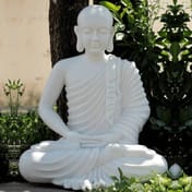 Meditating monk garden statue in white in a garden