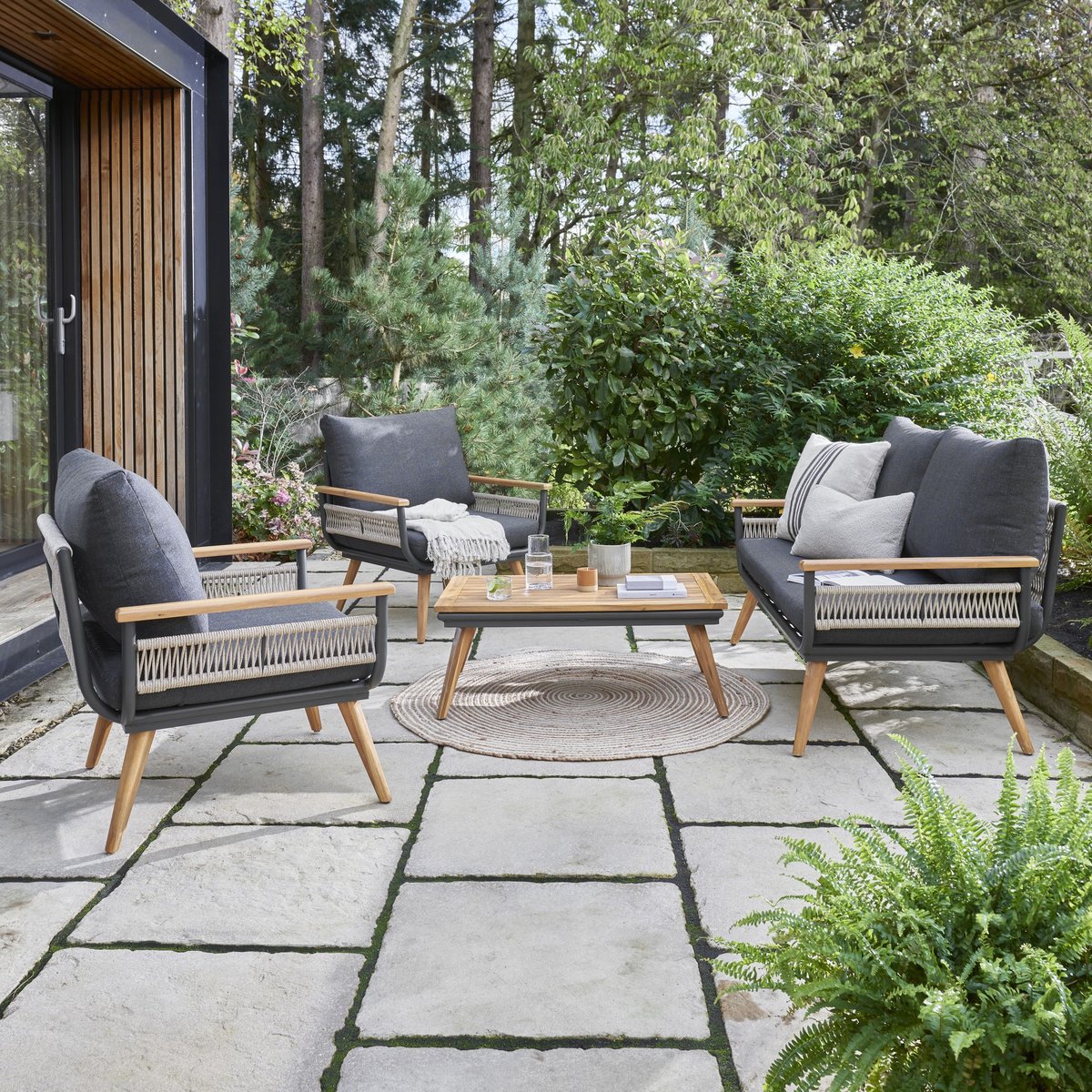 Norfolk Collection Kimora 4 seat rattan garden lounge set with grey cushions, separate sofa and armchairs on a UK lawn