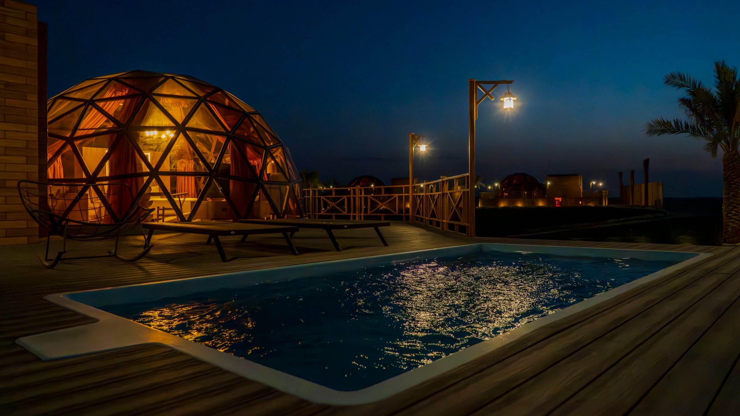 A private pool lit at dusk, the dome glowing behind it against a deep blue sky