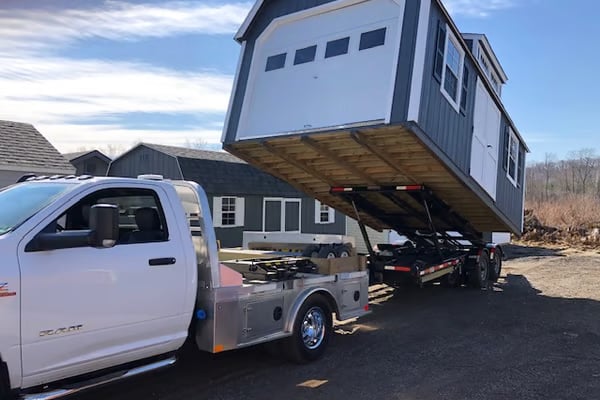 A photo of a truck dropping off a shed for delivery and shed installation