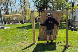 A Capitol Sheds crew member removing and replacing a fence during shed installation
