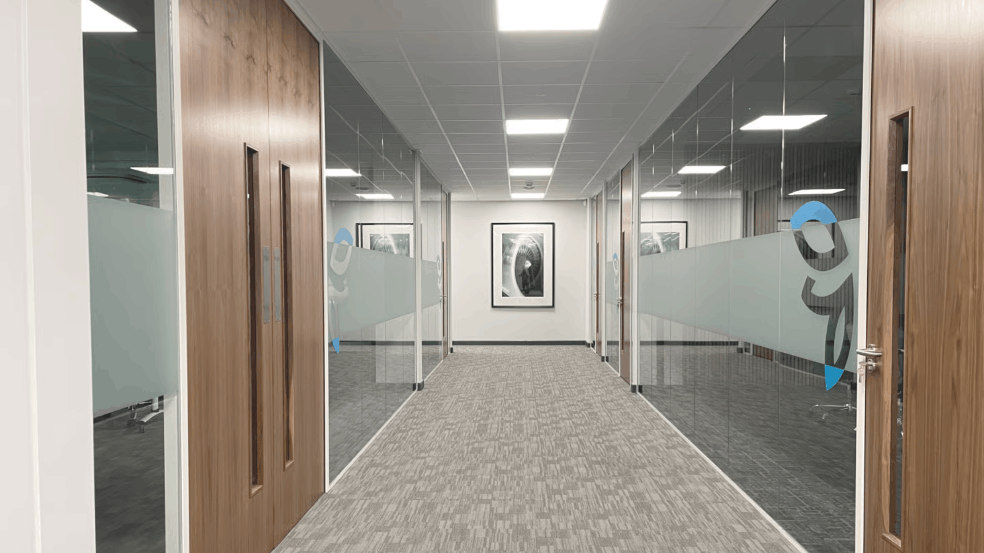 Glass office partitioning with frosted privacy panels, wooden doors, and modern meeting room layout