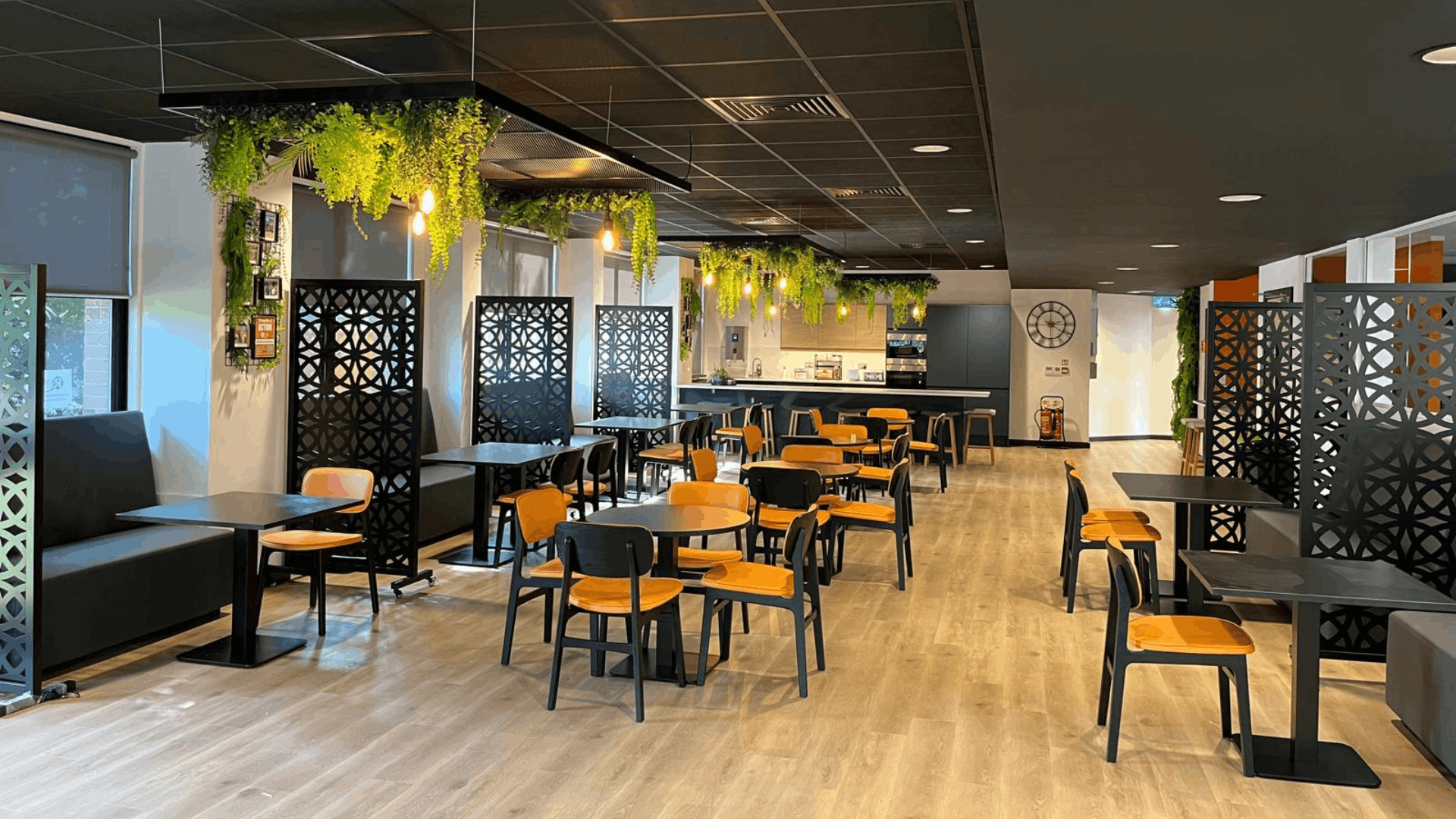 Riviera travel breakout area with black ceiling, orange seating, privacy screens and central tea point