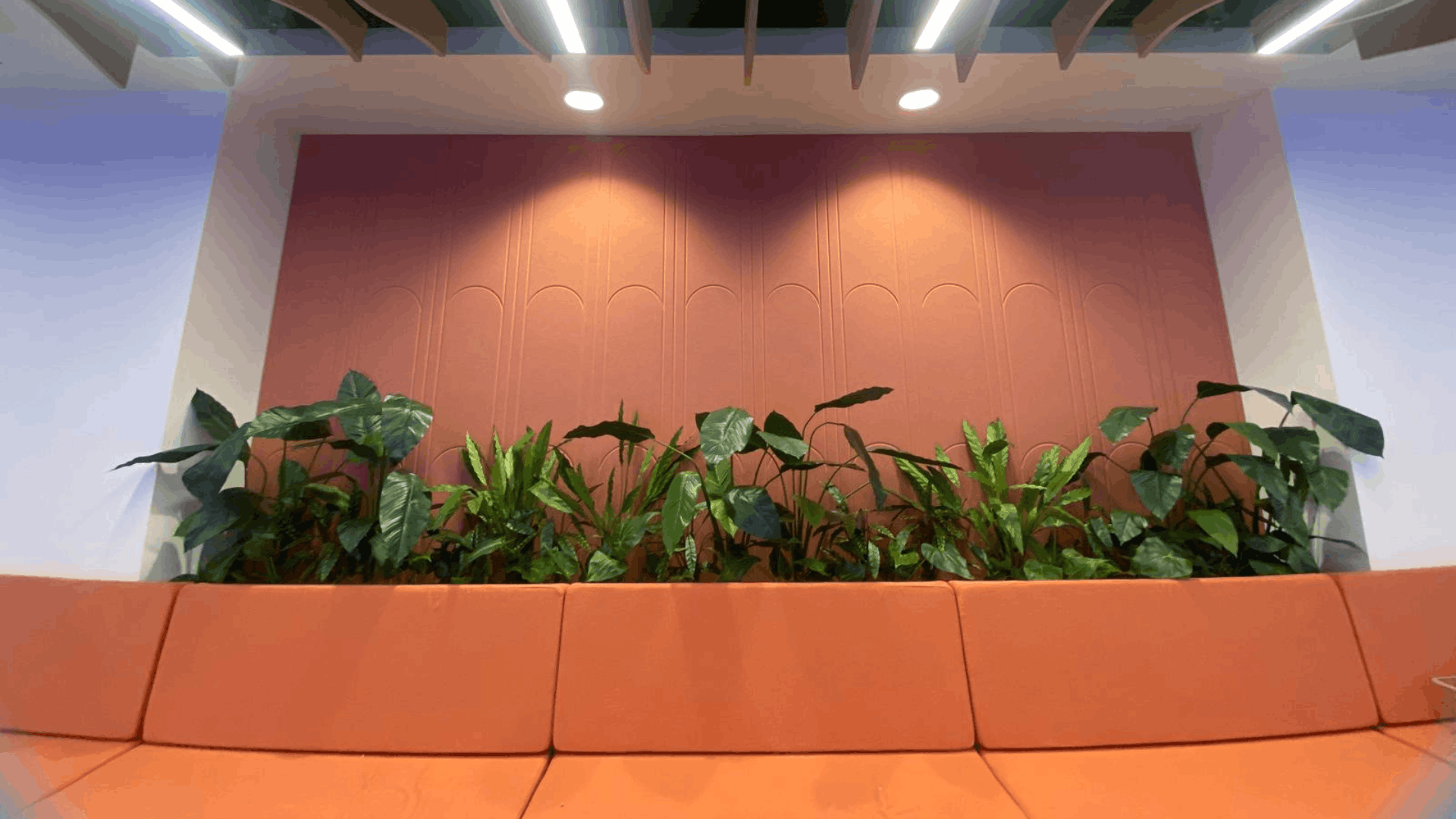 Built-in orange seating, indoor planting and terracotta acoustic wall panels in the nec media suite