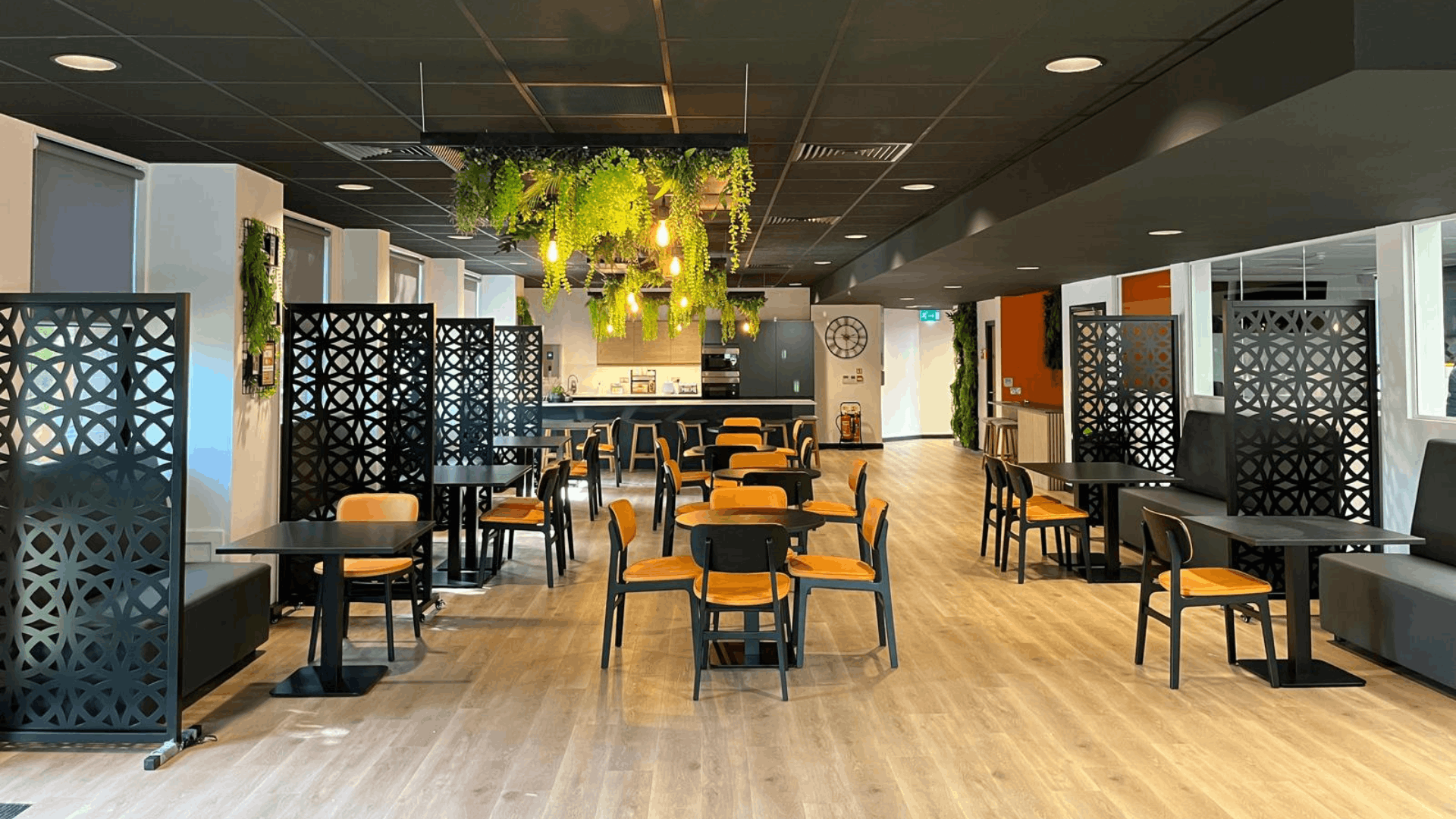 Modern riviera travel staff breakout space with black ceiling, feature planting, tea point and mixed seating