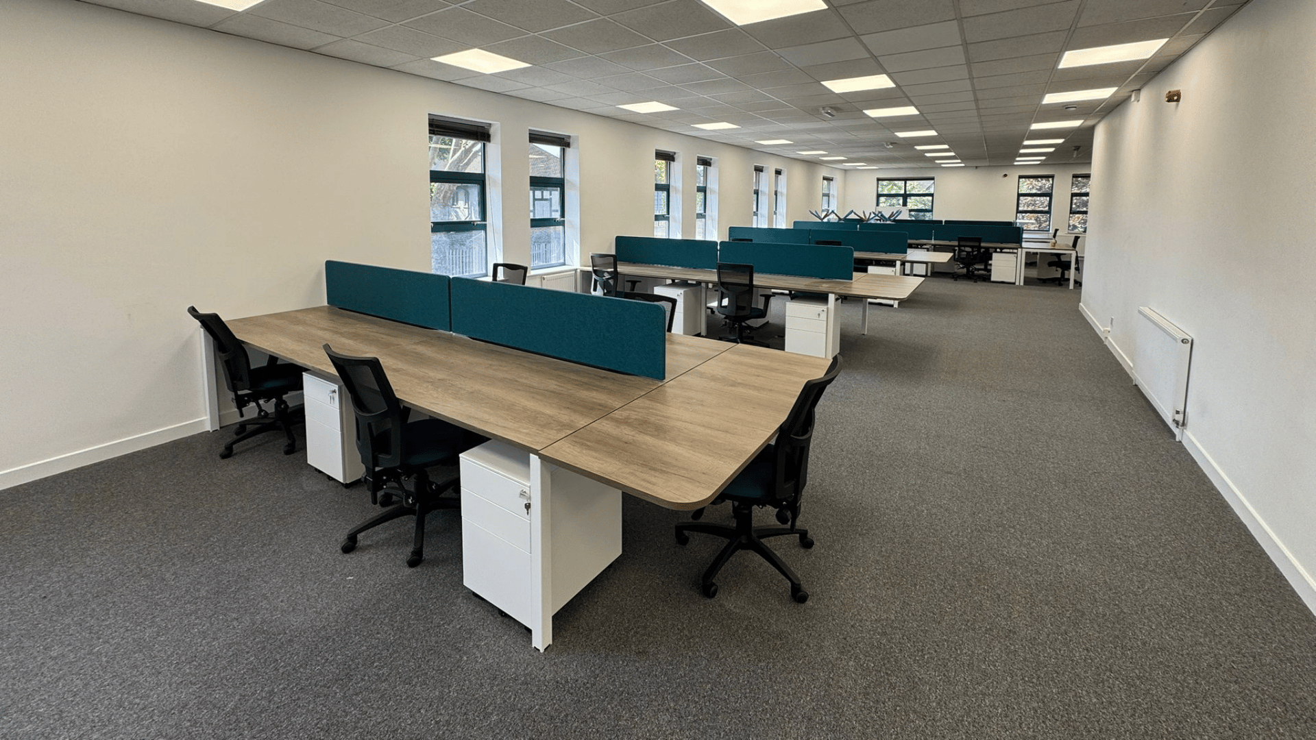 Open-plan workstation area completed as part of the dsl systems office fit out with desks, task chairs, teal desk screens and storage pedestals