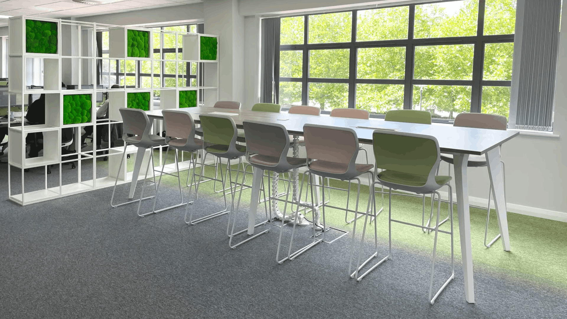 Modern office furniture installation with collaborative seating, high desks, and green acoustic feature panels