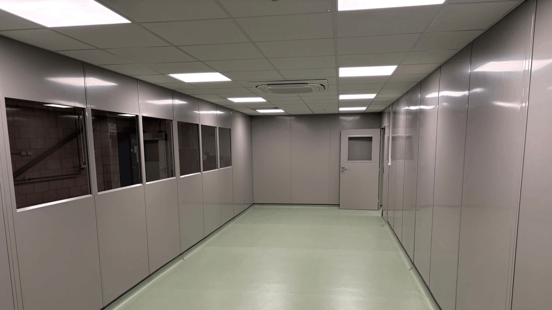 Clean room corridor with glazed steel partitioning, suspended ceiling, air conditioning cassette and safety vinyl flooring.