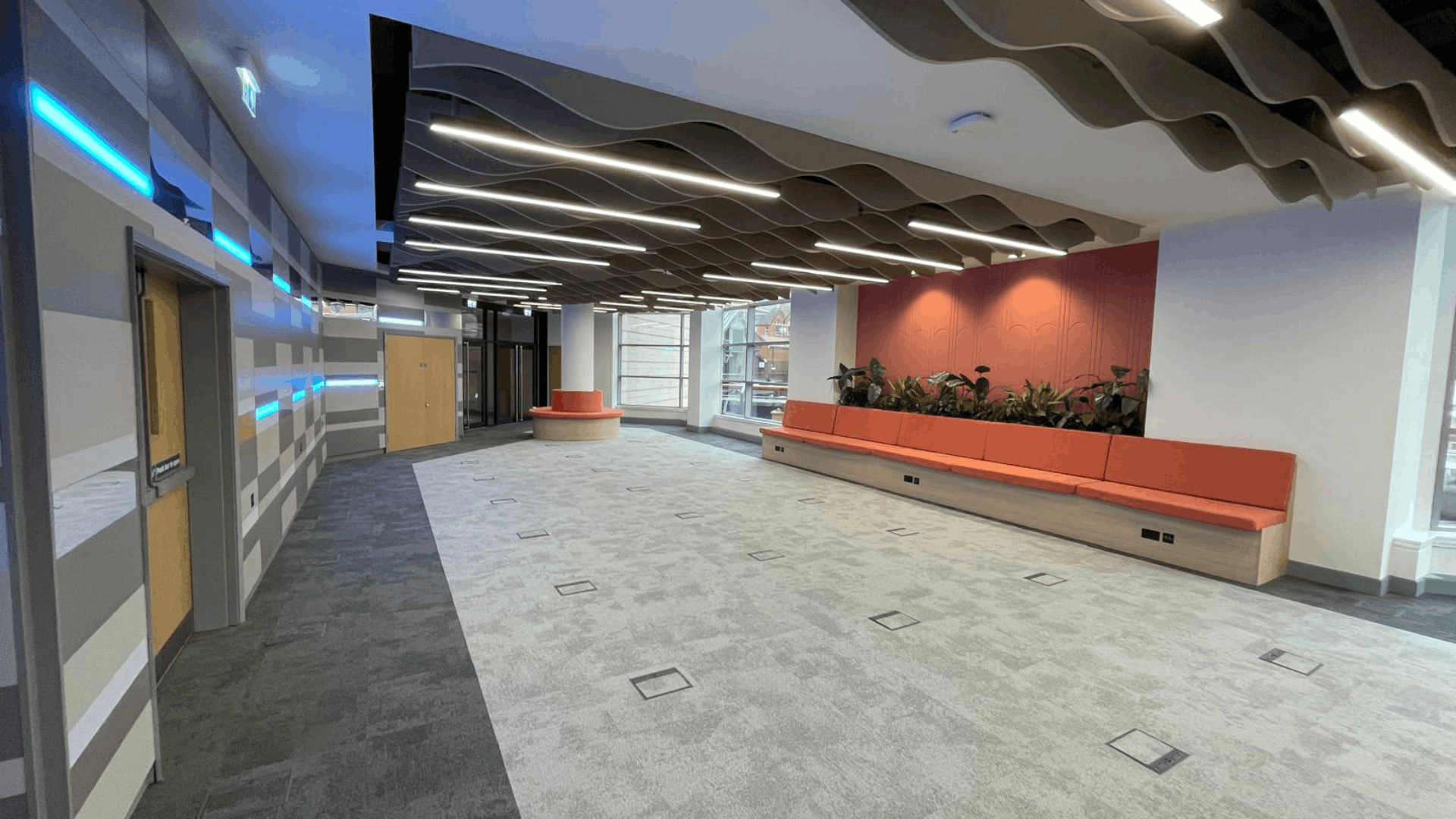 Open-plan nec media suite workspace with acoustic wave ceiling, feature lighting and built-in seating