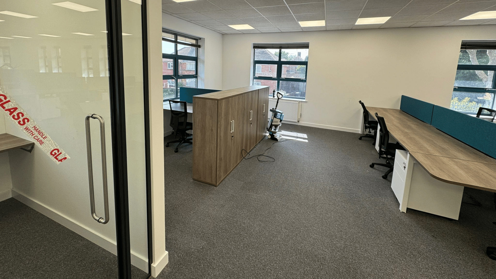 Office furniture and storage installed for the dsl systems office fit out with desks, chairs, teal screens and wooden storage units near the windows