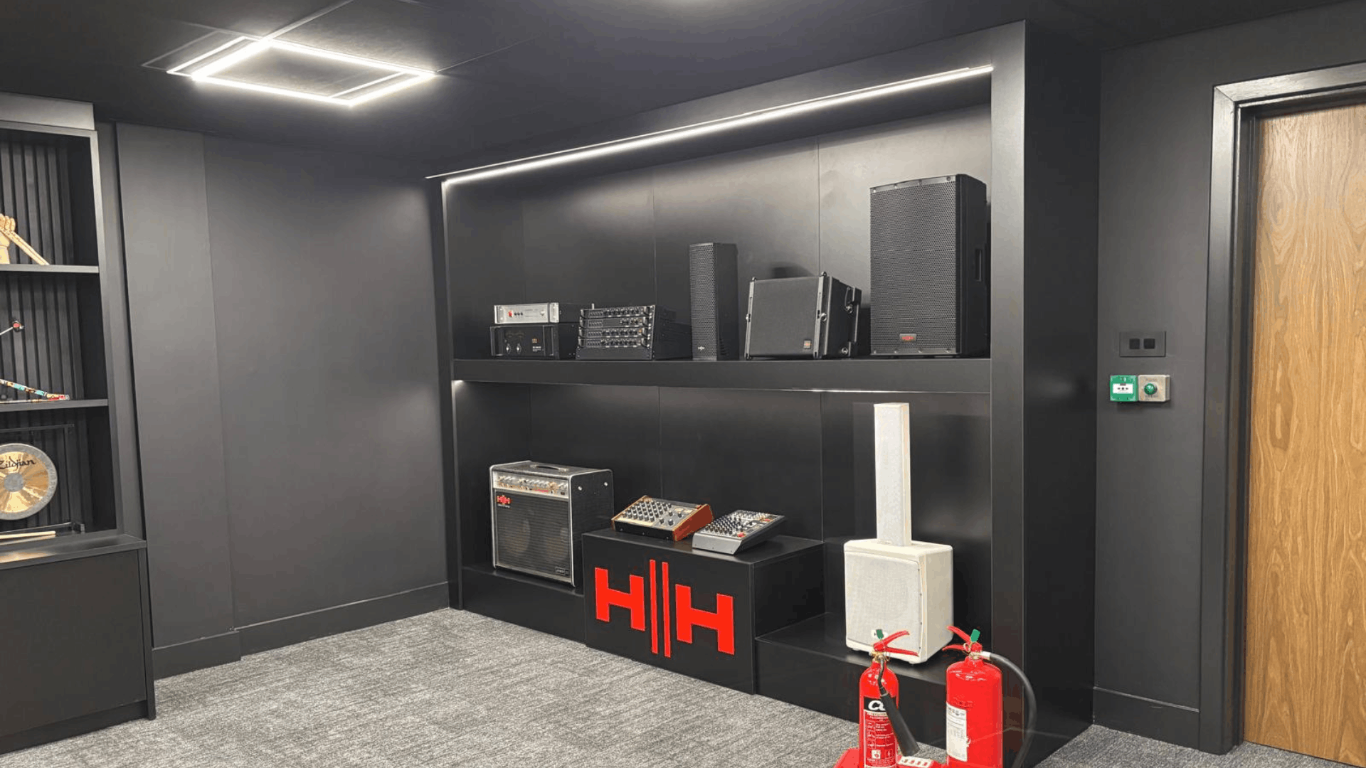 Headstock group office refurbishment featuring bespoke black product display wall with audio equipment and branded plinth