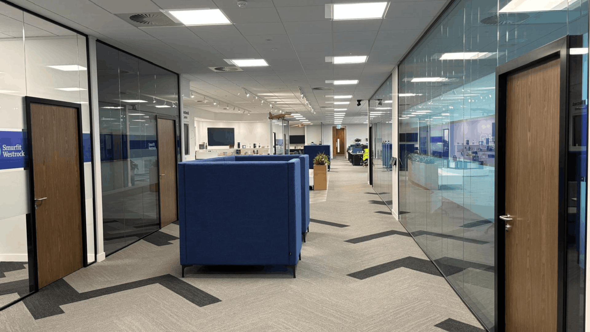 Completed smurfit westrock office corridor with glass partitions, walnut doors and acoustic meeting booths