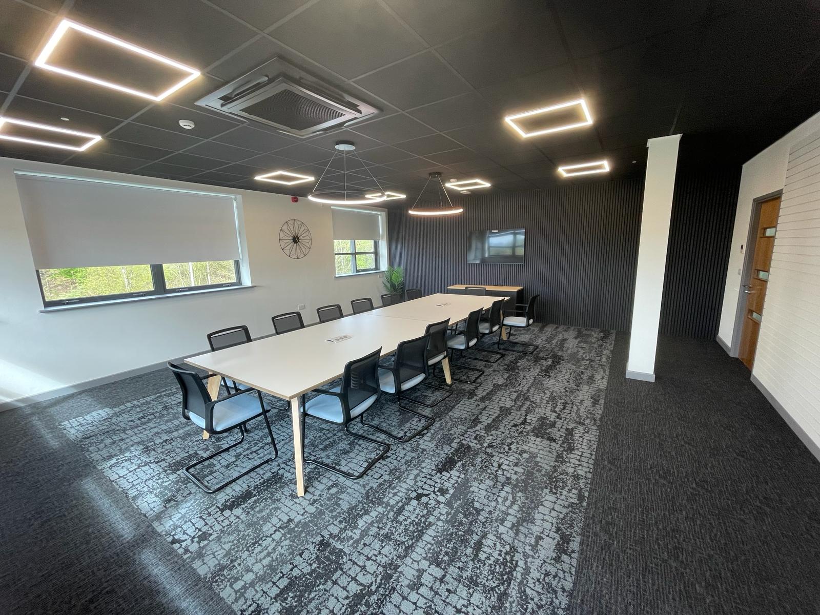 First floor boardroom at card factory wakefield with black feature ceiling, pendant lighting, slatted wall panels and a large meeting table