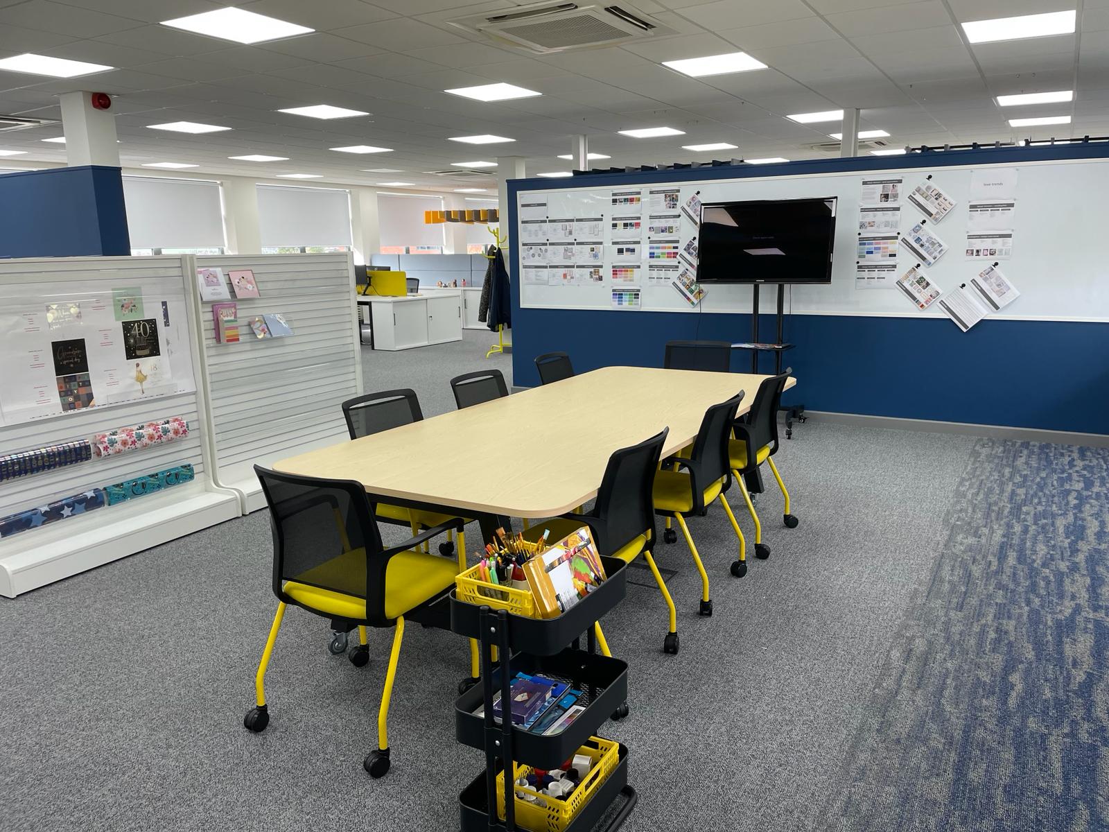 Creation zone at card factory wakefield with meeting table, display stands, wall mounted screen and magnetic write on wall