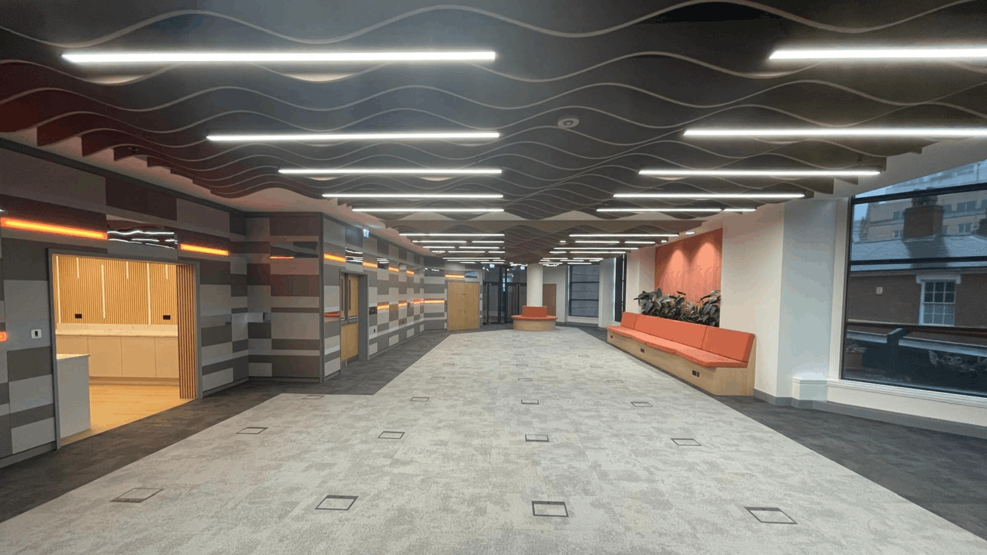 Refurbished nec media suite interior with patterned acoustic ceiling, feature walls, led lighting and open workspace