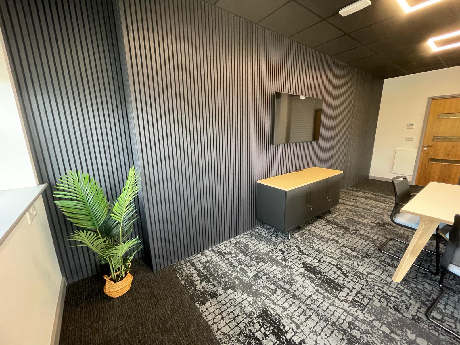 Card factory wakefield boardroom with decorative charcoal slatted wall panels, patterned carpet tiles and wall mounted display screen