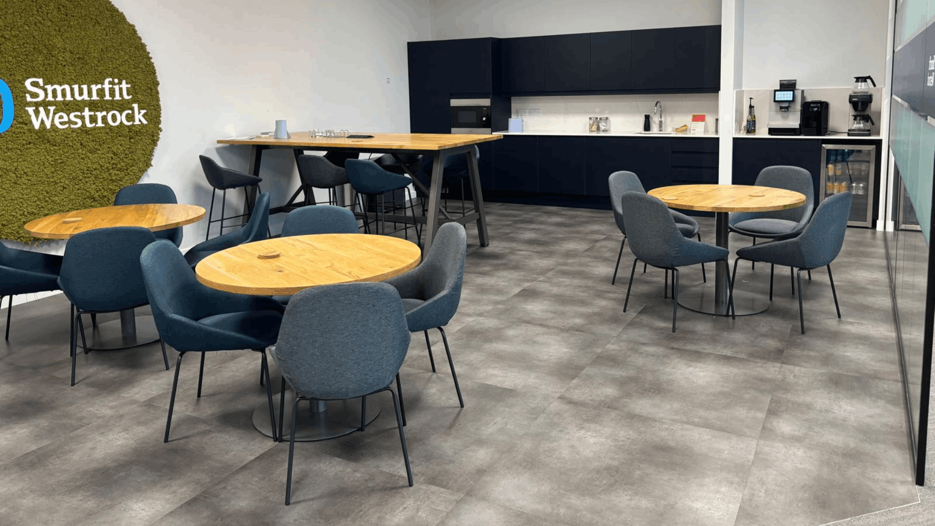 Smurfit westrock breakout area with moss feature wall, timber tables, blue chairs and black tea point