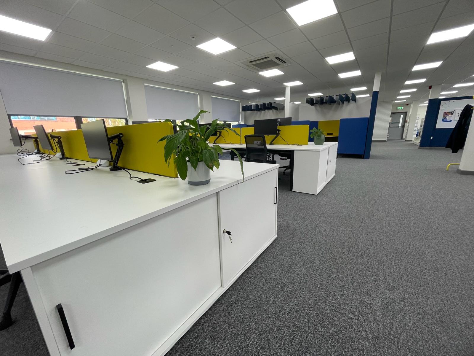 Refurbished open plan office at card factory wakefield with new carpet tiles, white bench desks and yellow acoustic desk screens