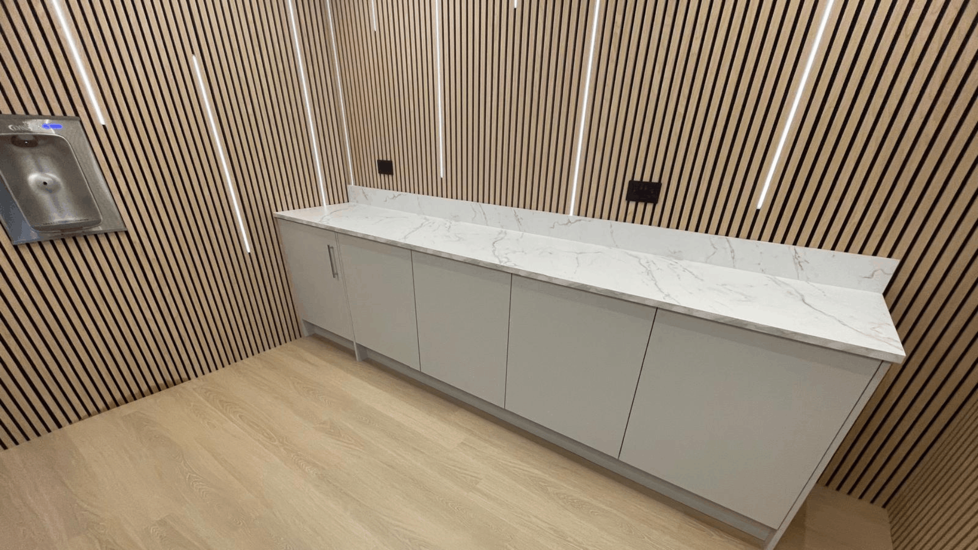 Modern tea point with timber slat wall panels, marble-effect worktop and fitted storage in the nec media suite