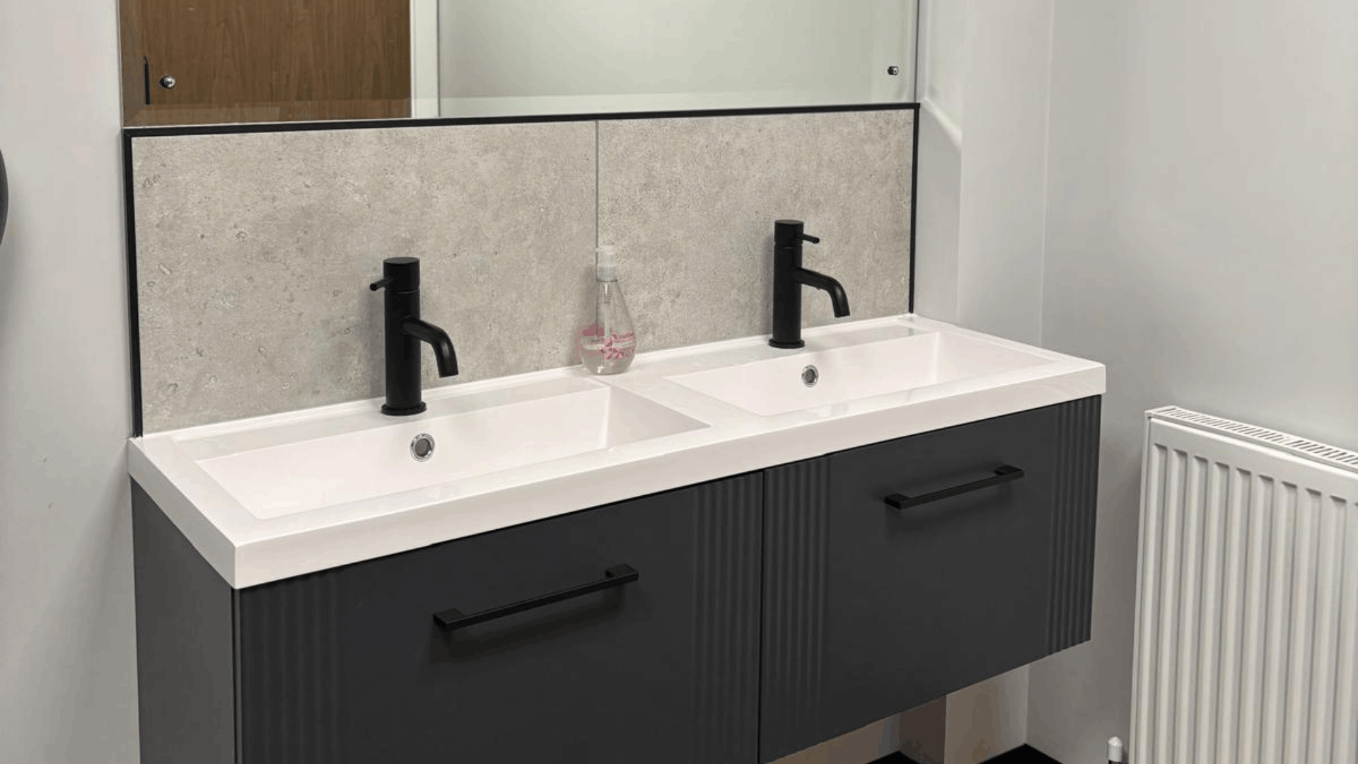 Refurbished headstock group washroom vanity unit with twin basins, black taps, grey panelling and large mirror
