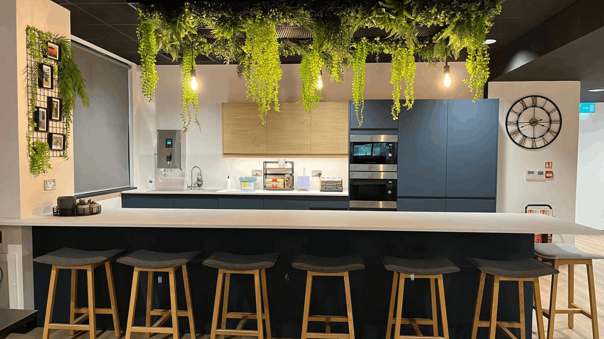 Riviera travel tea point with breakfast bar, timber stools, blue-grey cabinetry and suspended planting