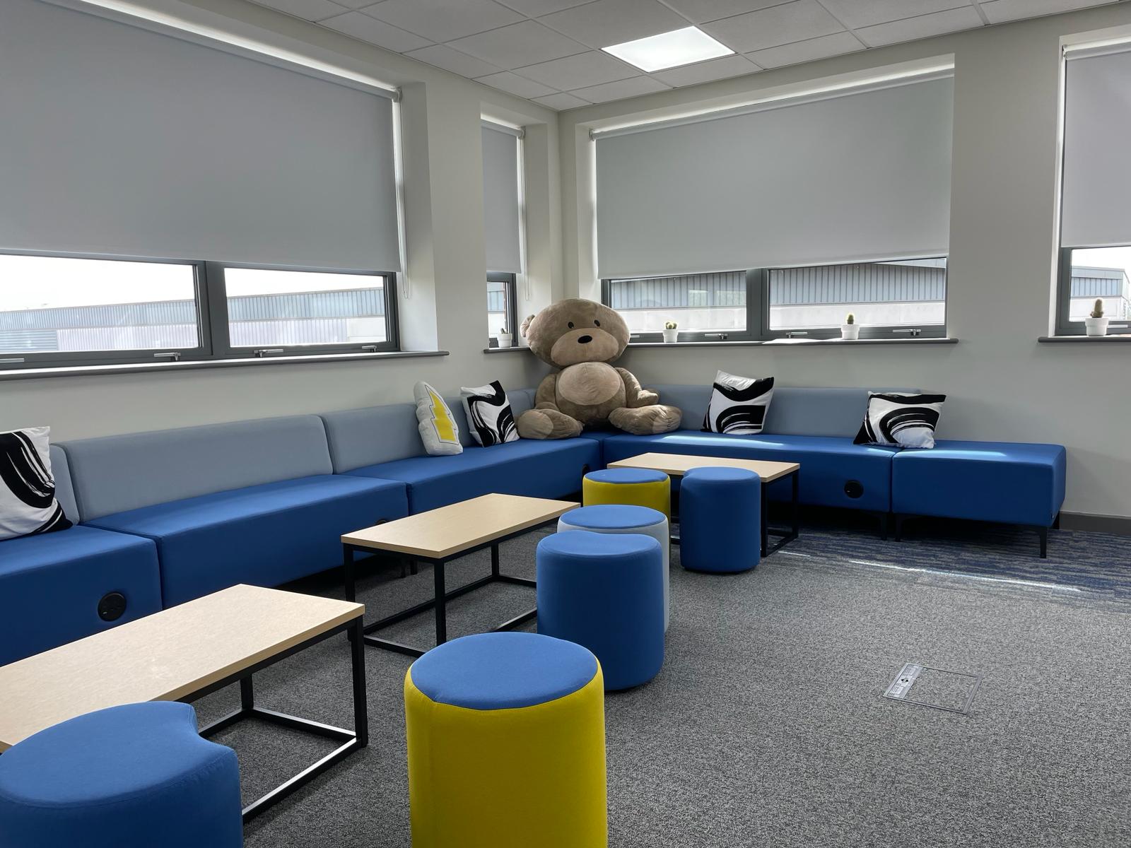 Informal breakout area at card factory wakefield with blue bench seating, pouffes, coffee tables and soft furnishings