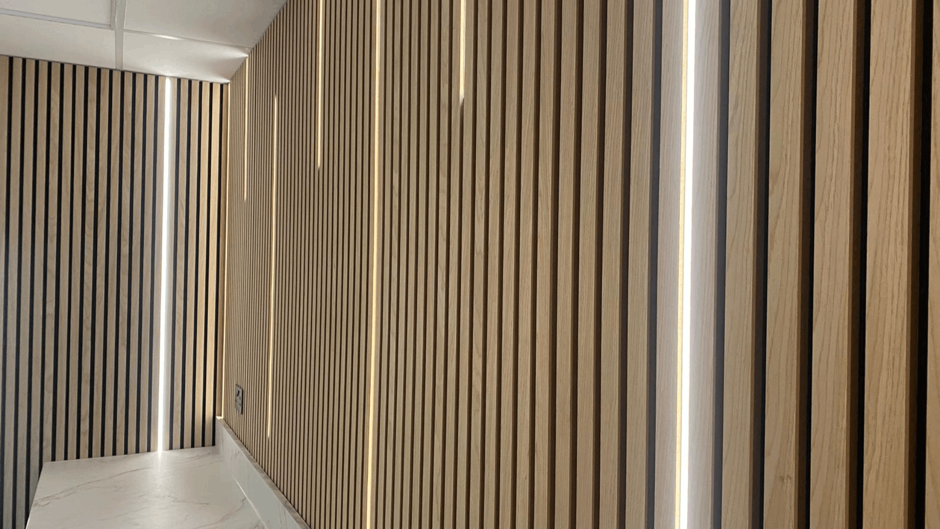 Timber slat feature wall with integrated vertical lighting in the nec media suite office interior