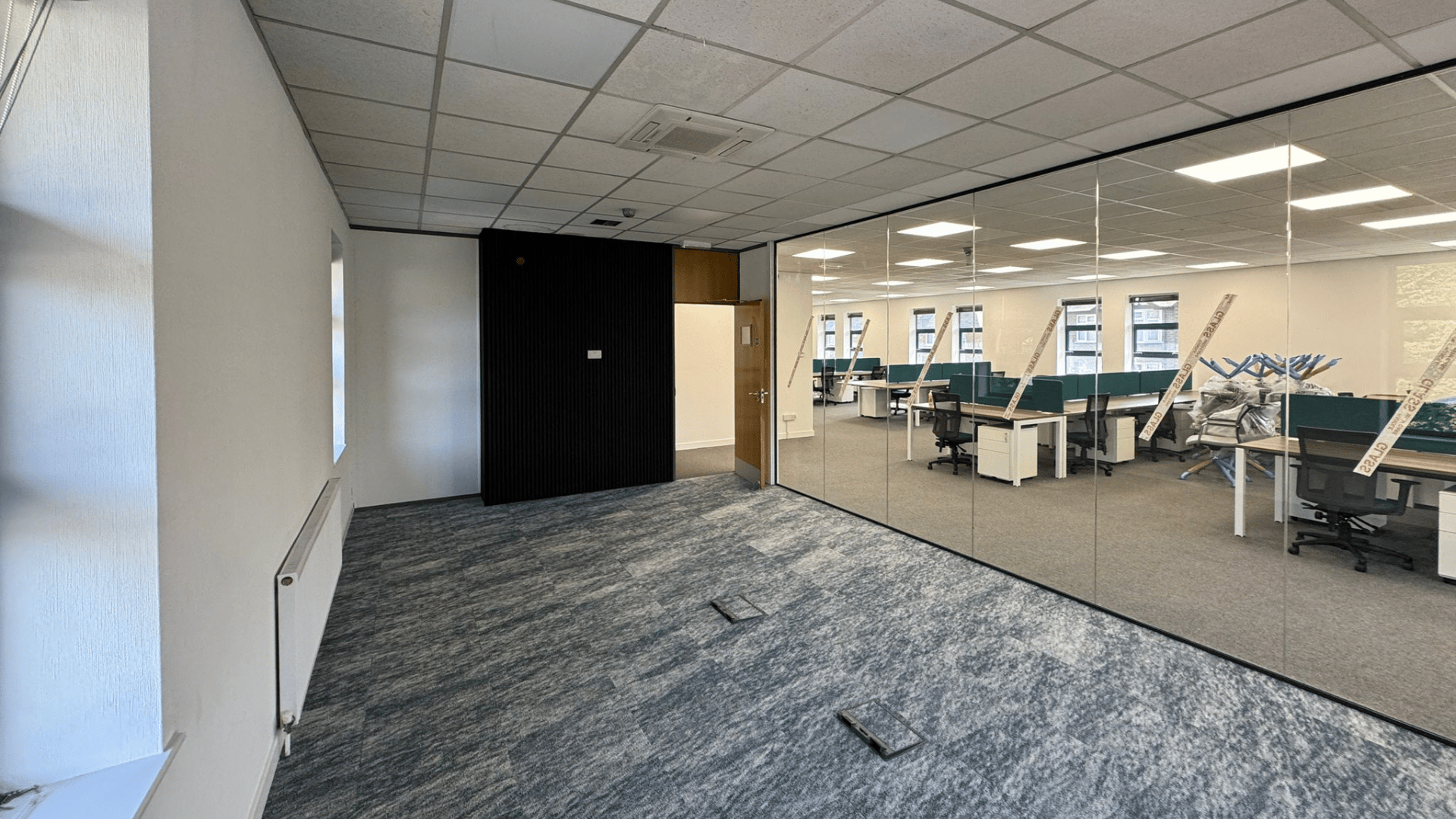 Glazed boardroom installed during the dsl systems office fit out with feature carpet, black wall panelling and views into the open-plan workspace