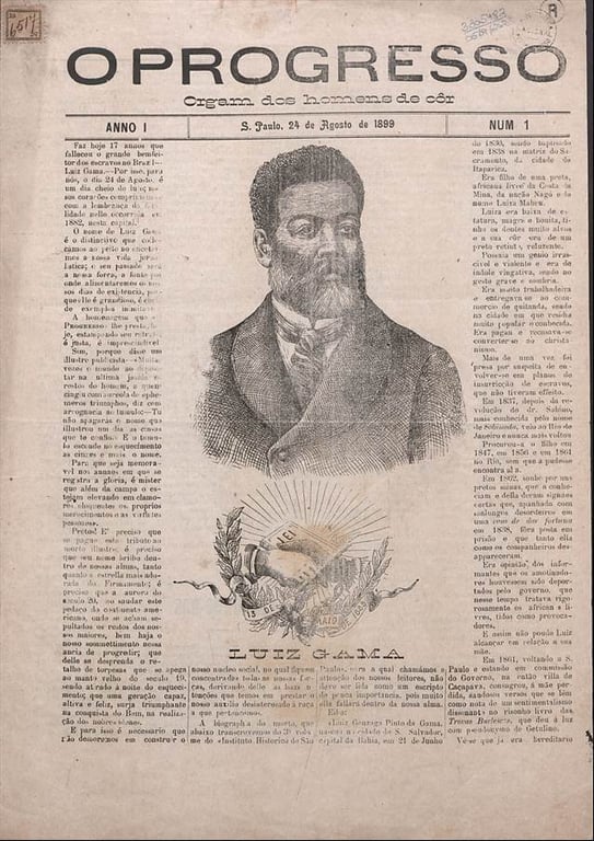Imagem da capa do jornal histórico O Progresso do Estado de São Paulo, com o subtítulo 'Órgam dos homens de cor'. A edição é datada de 24 de agosto de 1899 e está impressa em papel amarelado, com aparência antiga. No centro da página, há uma grande ilustração em tons de preto e cinza de Luiz Gama, homem negro de barba cheia, cabelos curtos e crespos, vestindo paletó e camisa com gola alta. Abaixo do retrato, há o nome 'Luiz Gama' em letras maiusculas. Ao redor do nome, um brasão com folhas de louro envolve dois livros abertos, um deles com a inscrição 'Lei', iluminados por raios de luz. A página está repleta de colunas de texto impresso em fonte serifada. Esta edição do jornal celebra Luiz Gama no 17º ano de seu falecimento.