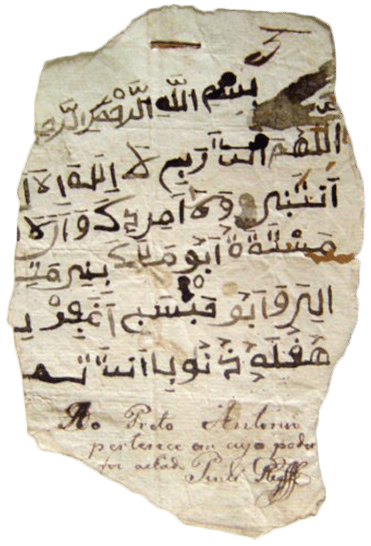 Fragmento de manuscrito em árabe apreendido com Preto Antônio após a Revolta dos Malês, pertencente ao Arquivo Público do Estado da Bahia. O documento é um pedaço irregular de papel envelhecido, com bordas rasgadas e desgastadas pelo tempo. A maior parte da superfície é ocupada por linhas de escrita em árabe, feitas com tinta escura e distribuídas horizontalmente. Em alguns pontos, o papel apresenta manchas, pequenos furos e marcas de deterioração. Na parte inferior, abaixo do texto em árabe, há uma anotação manuscrita em português, escrita com tinta mais clara e caligrafia cursiva. O fragmento preserva registros da escrita utilizada por africanos muçulmanos envolvidos na Revolta dos Malês, ocorrida em Salvador, em 1835.