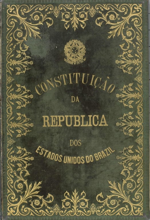 Capa original da Constituição da República dos Estados Unidos do Brazil, de 1891. O fundo é verde-escuro com detalhes ornamentais dourados em estilo floral e arabesco contornando as bordas. No centro, está o título em letras douradas e serifadas. Acima, vê-se o brasão da República do Brasil, também em dourado. O design transmite solenidade e importância, refletindo a transição do império para a república e a tentativa de consolidar uma nova ordem constitucional inspirada nos ideais republicanos e liberais.