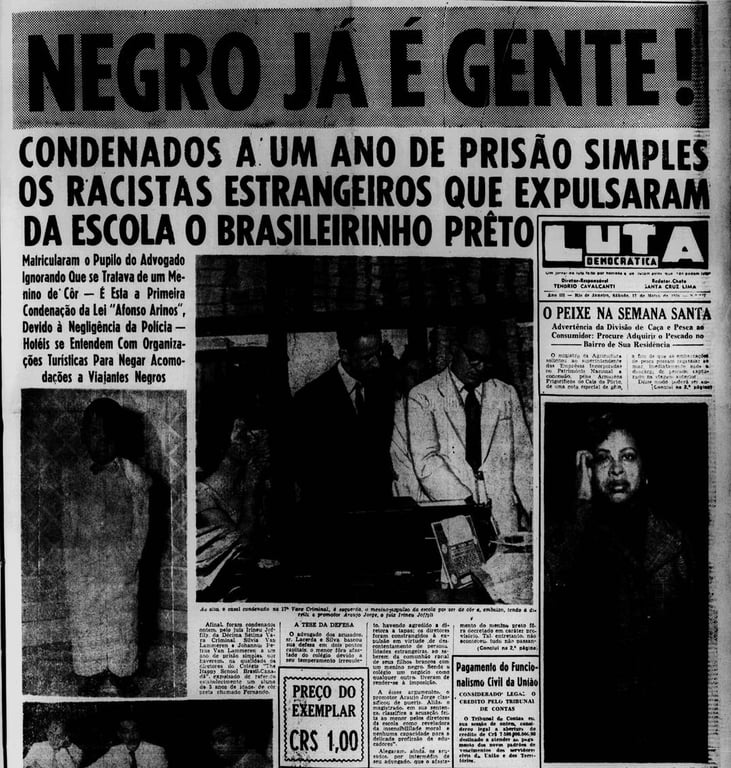 A imagem é a fotografia de uma página de jornal antigo, com forte contraste em preto e branco. O título principal, em letras enormes e impactantes, diz: 'NEGRO JÁ É GENTE!'. Logo abaixo, em destaque, aparece o subtítulo: 'Condenados a um ano de prisão simples os racistas estrangeiros que expulsaram da escola o brasileirinho preto'. O jornal noticia a primeira condenação realizada com base na Lei Afonso Arinos, legislação pioneira no combate à discriminação racial no Brasil (1951). O texto explica que estrangeiros responsáveis por expulsar um menino negro de uma escola foram julgados e punidos, destacando a importância do caso e a negligência de autoridades e estabelecimentos que ainda permitiam práticas discriminatórias. A página também contém pequenas fotografias relacionadas ao caso – retratos de pessoas envolvidas e a cena do tribunal – além de colunas informativas, anúncios e o preço do exemplar (Cr$ 1,00). A diagramação típica de jornais da metade do século XX reforça o caráter histórico e crítico da reportagem, marcada por uma linguagem combativa em defesa dos direitos da população negra.