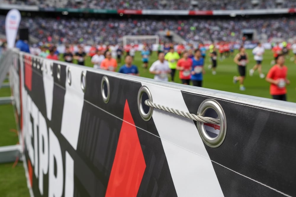 Sports event stadium banners and marathon flags using 18-25mm stainless steel grommets supporting large-format 3m x 6m banners, exceeding stadium safety standards with 80kg load capacity, used in 2023 Regional Marathon with zero grommet failures
